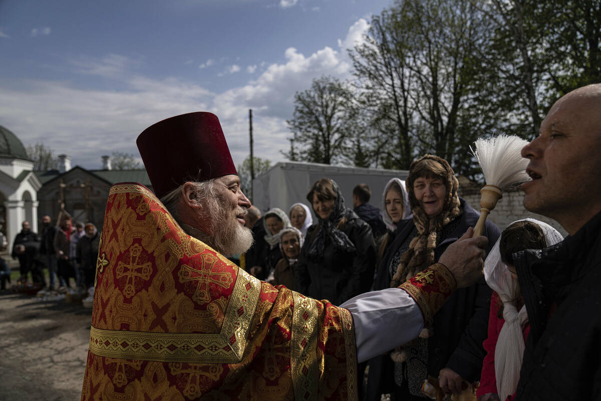 An Orthodox priest blesses believers during the Easter celebration at the All Saints church in ...
