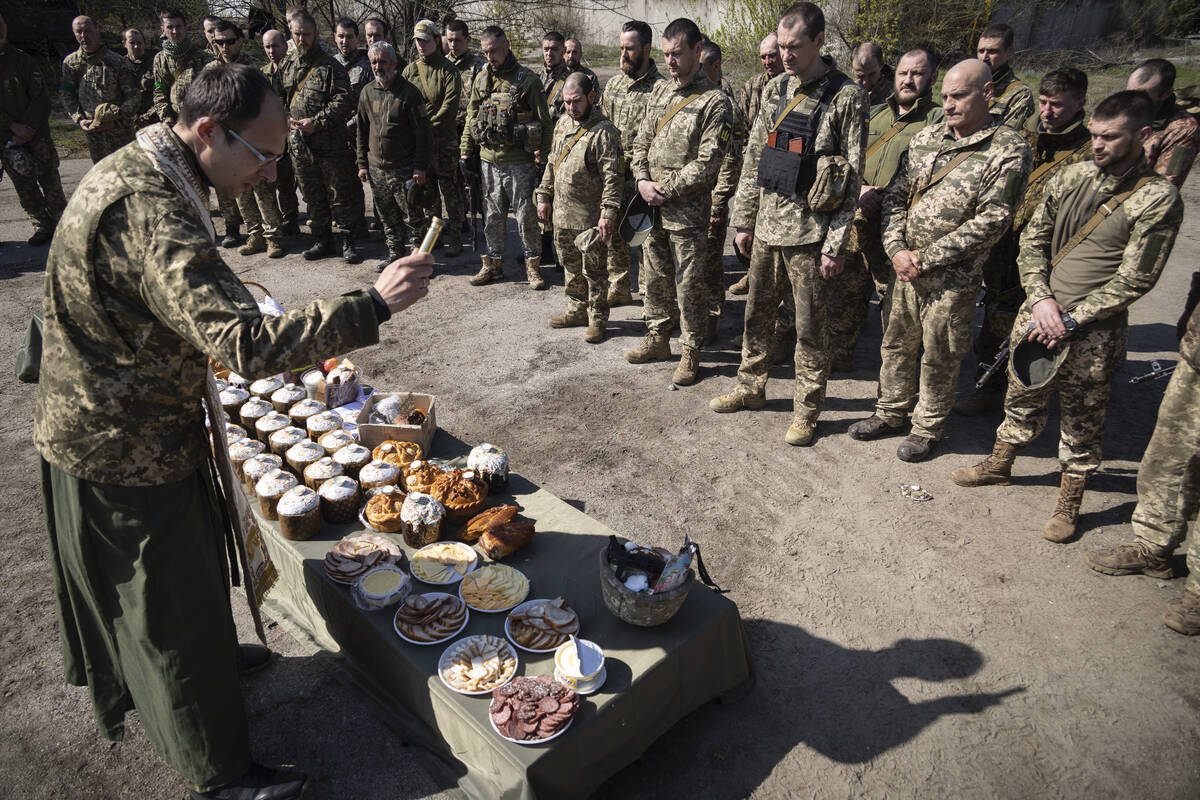 A military Orthodox priest blesses traditional food during the Easter celebration at the frontl ...