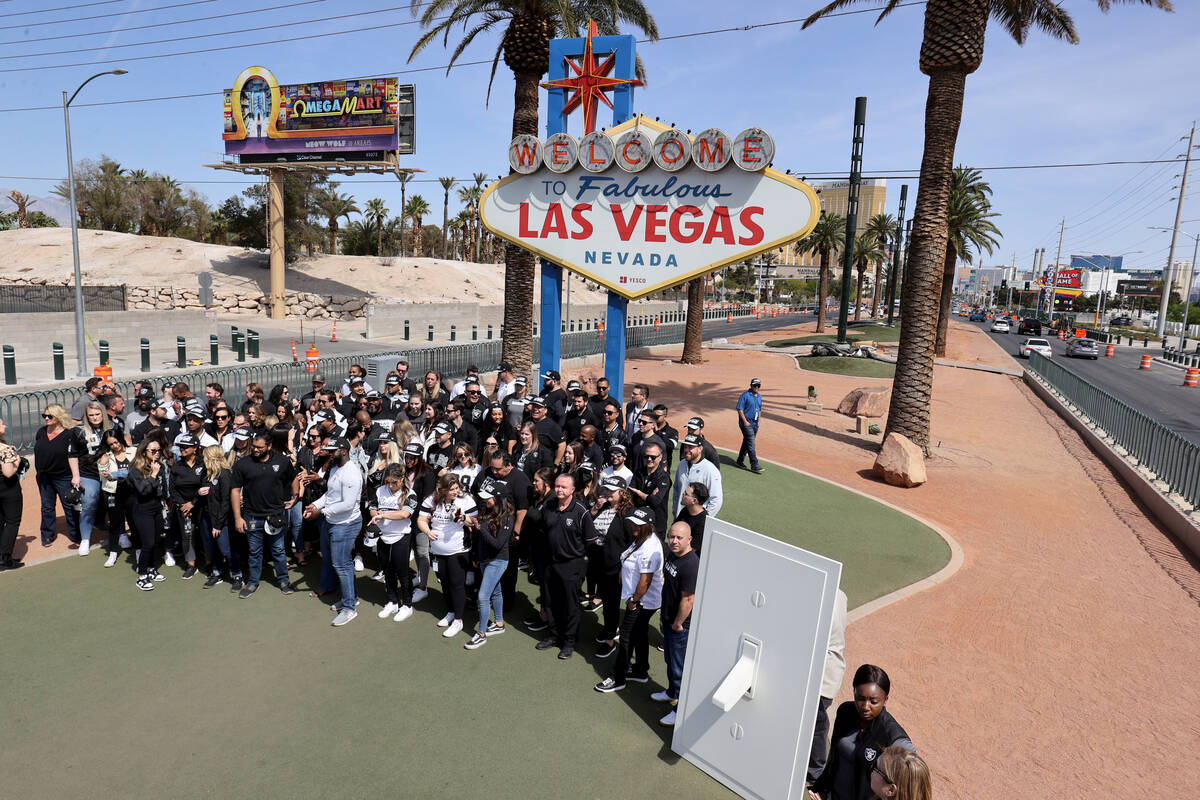 Raiders staff gather at the Welcome to Fabulous Las Vegas sign for a ceremony to light the peri ...
