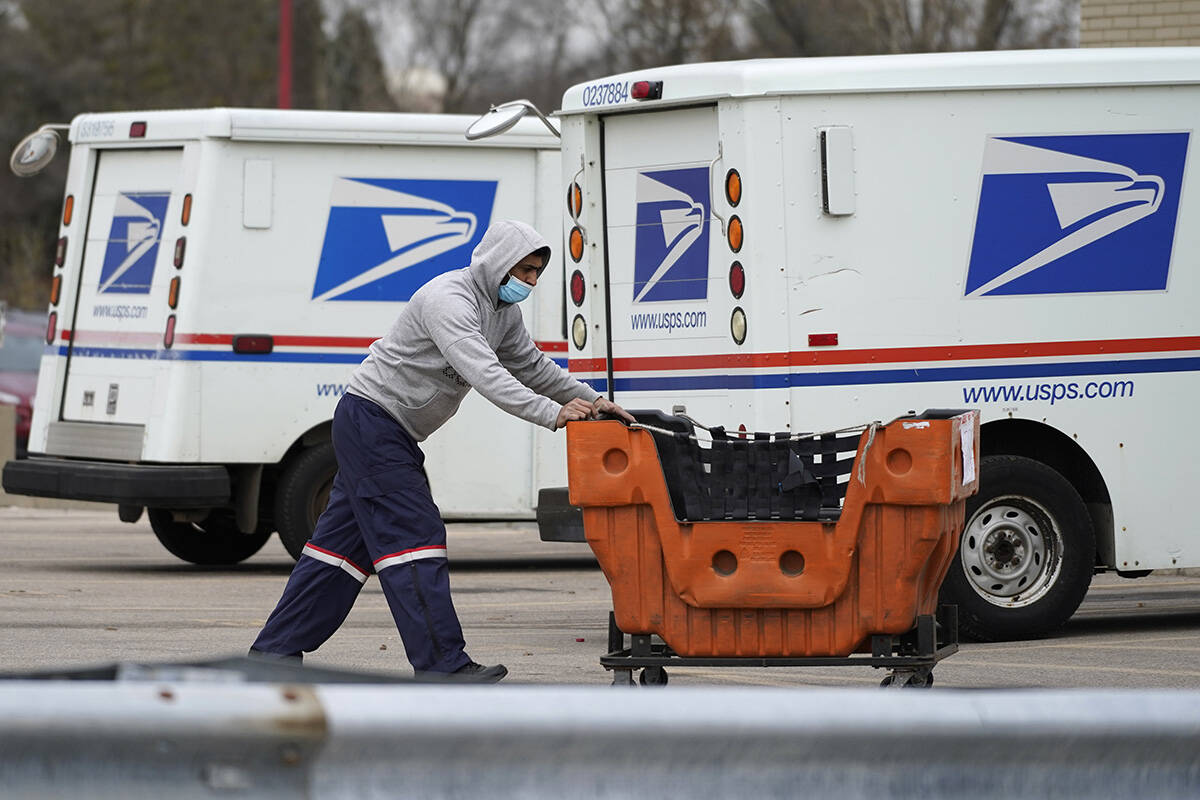 A United States Postal Service employee works outside a post office in Wheeling, Ill., Dec. 3, ...