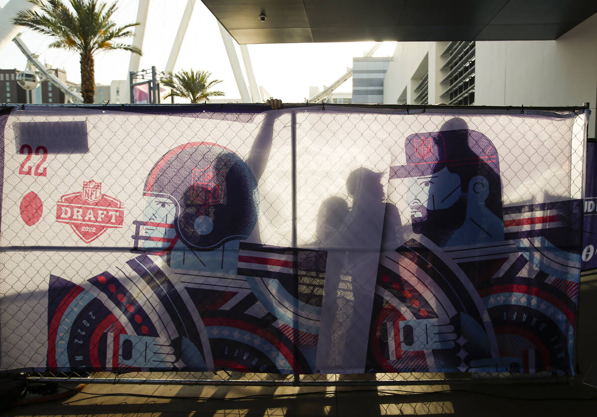 The shadows of fans are cast against the display during the first round of the NFL draft on Thu ...