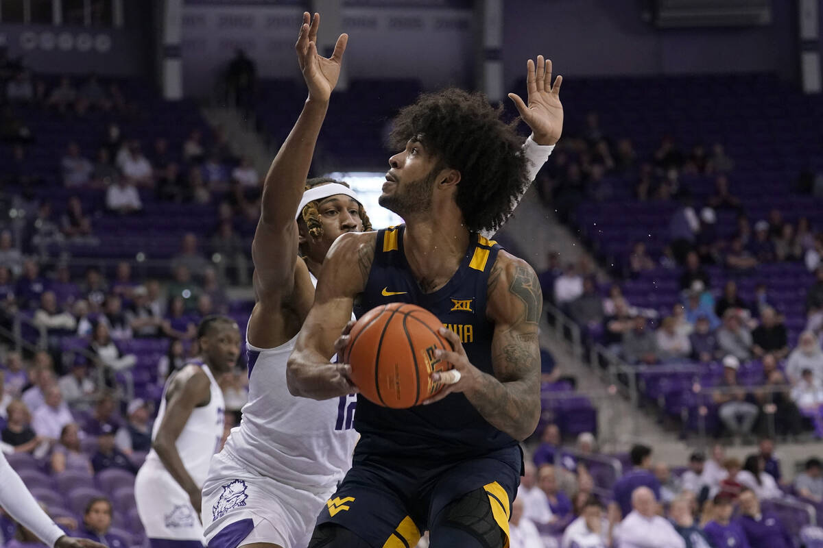 TCU forward Xavier Cork, left, defends as West Virginia forward Isaiah Cottrell (13) positions ...