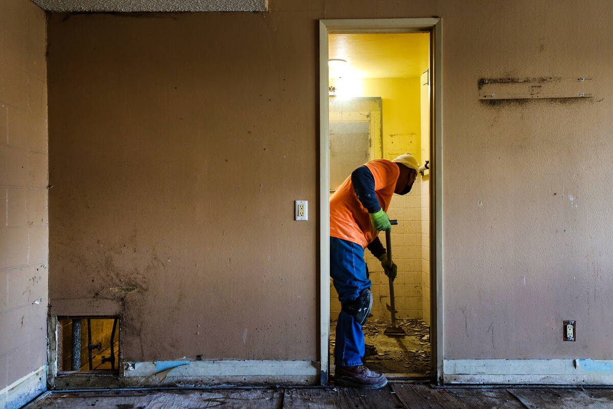 Juan Amador removes tiles in a bathroom of an apartment at the former Share Village 1 property ...
