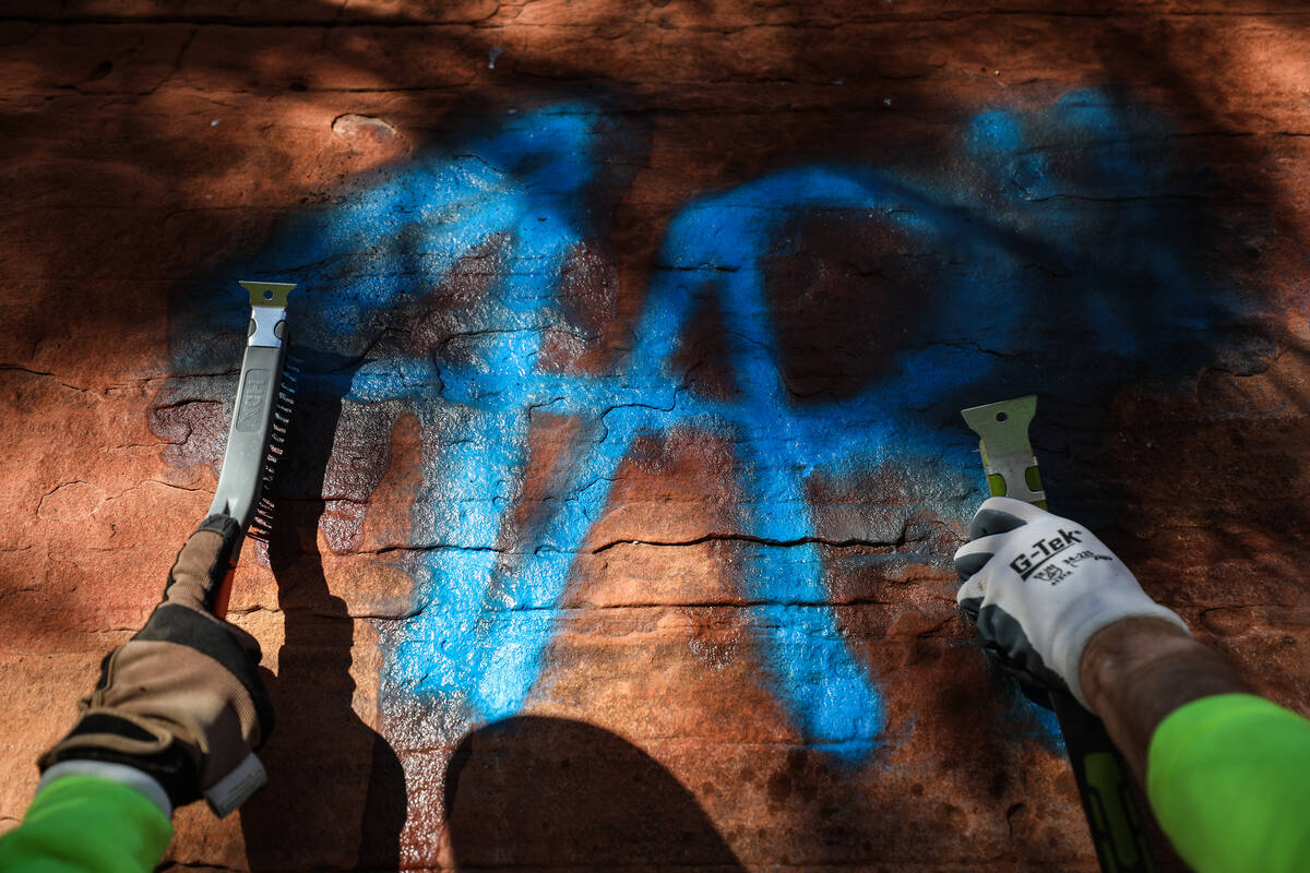 Volunteers Beth Schuck, left, and her husband Brian Schuck, right, remove graffiti along Ash Sp ...