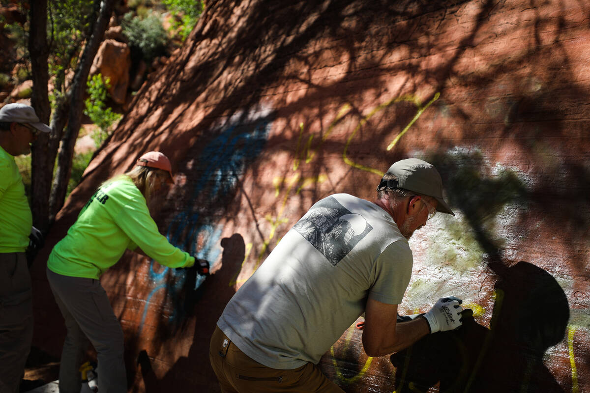 Volunteers work to remove graffiti along Ash Springs trail in Red Rock Canyon in Las Vegas, Sun ...