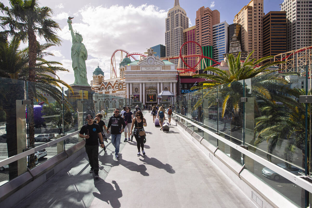 People walk along the pedestrian bridge between the New York-New York and the MGM Grand on Mond ...