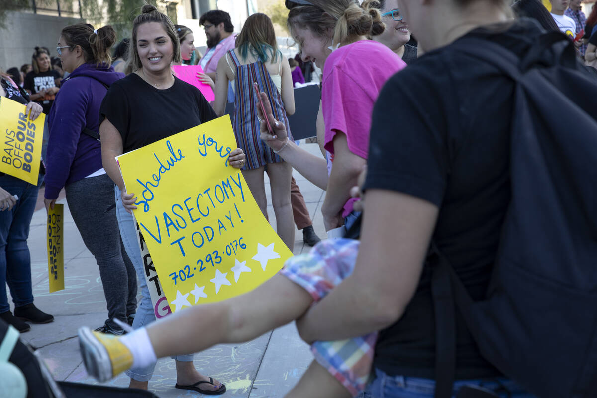 Lauren Busby, left, holds a sign listing her husband’s doctor’s phone number duri ...