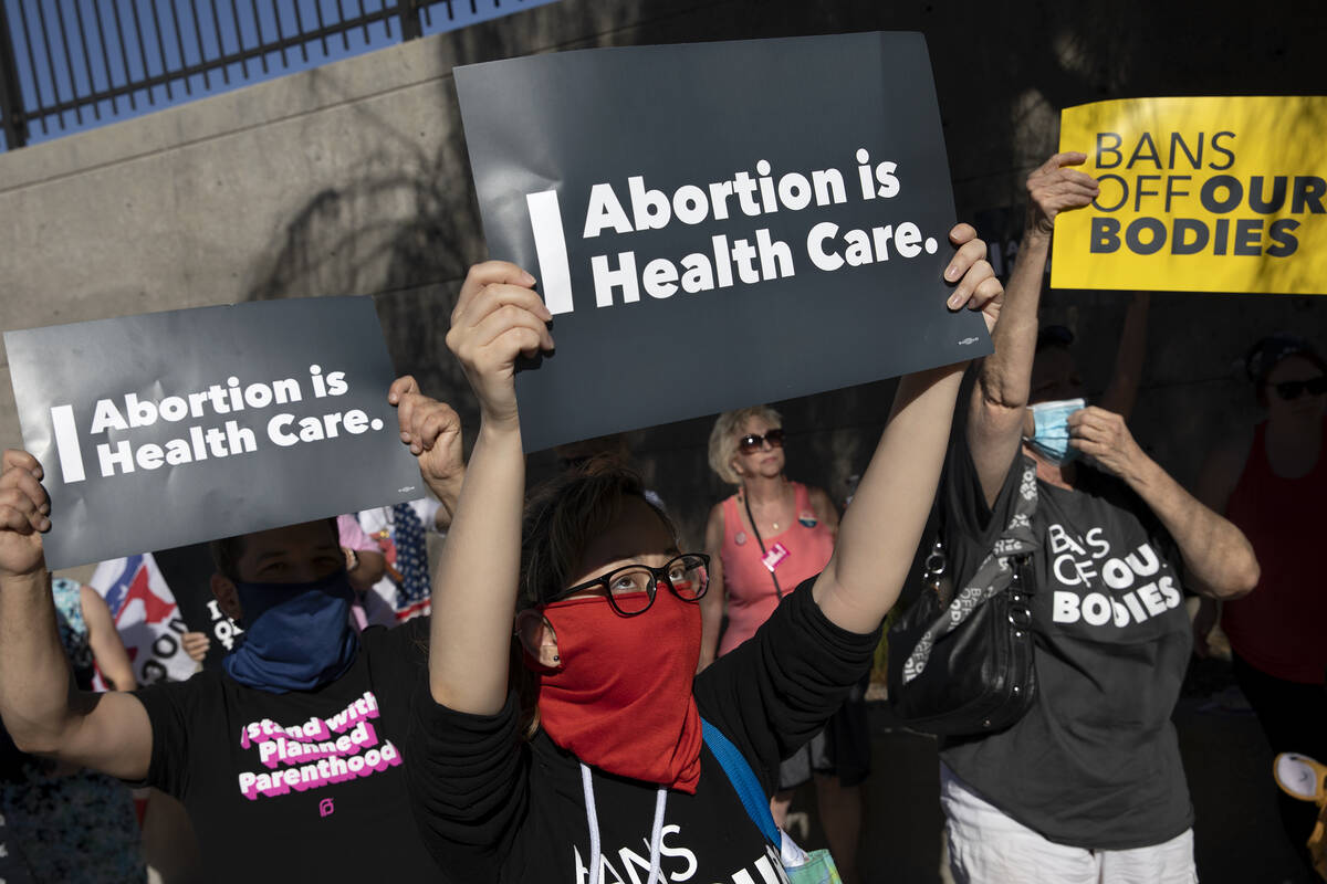 Attendees of a rally in support of abortion rights hold signs reading “abortion is healt ...