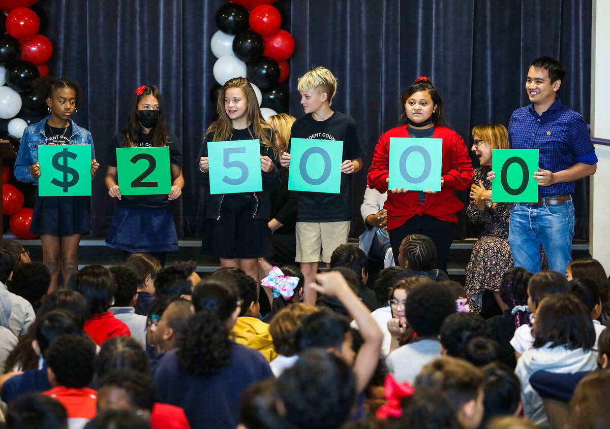 Students hold a sign of the cash prize of $25,000 at an assembly to present the Milken Educator ...
