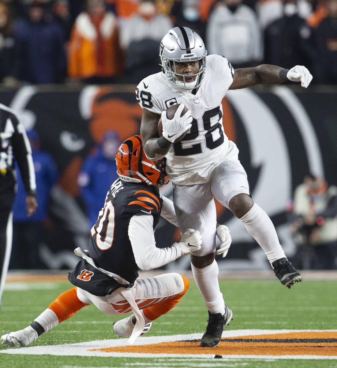 Raiders running back Josh Jacobs (28) runs as Cincinnati Bengals cornerback Eli Apple (20) look ...