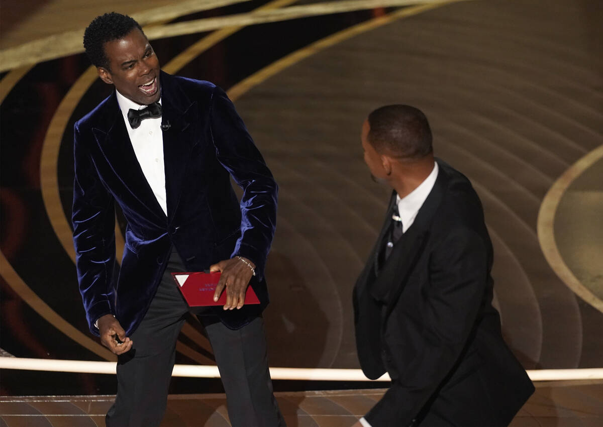 Presenter Chris Rock, left, reacts after being hit on stage by Will Smith while presenting the ...