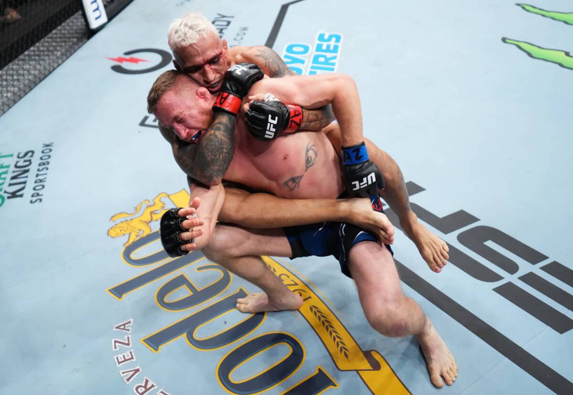 PHOENIX, ARIZONA - MAY 07: (R-L) Charles Oliveira of Brazil secures a rear choke submission aga ...