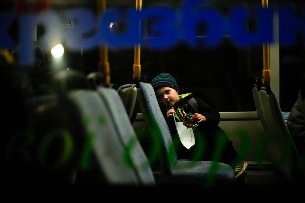A child who fled from Mariupol with his family waits in a bus upon their arrival at a reception ...