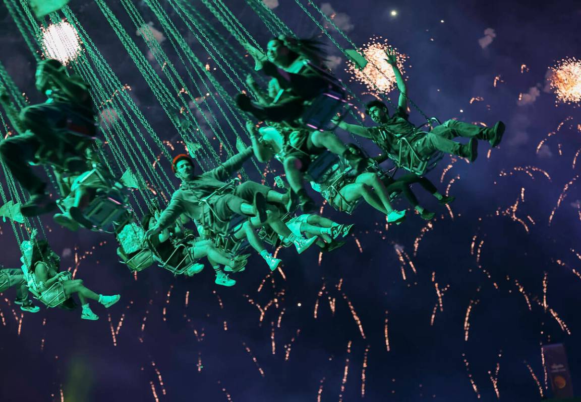 Attendees swing on a carnival ride as fireworks go off across the festival grounds during the s ...