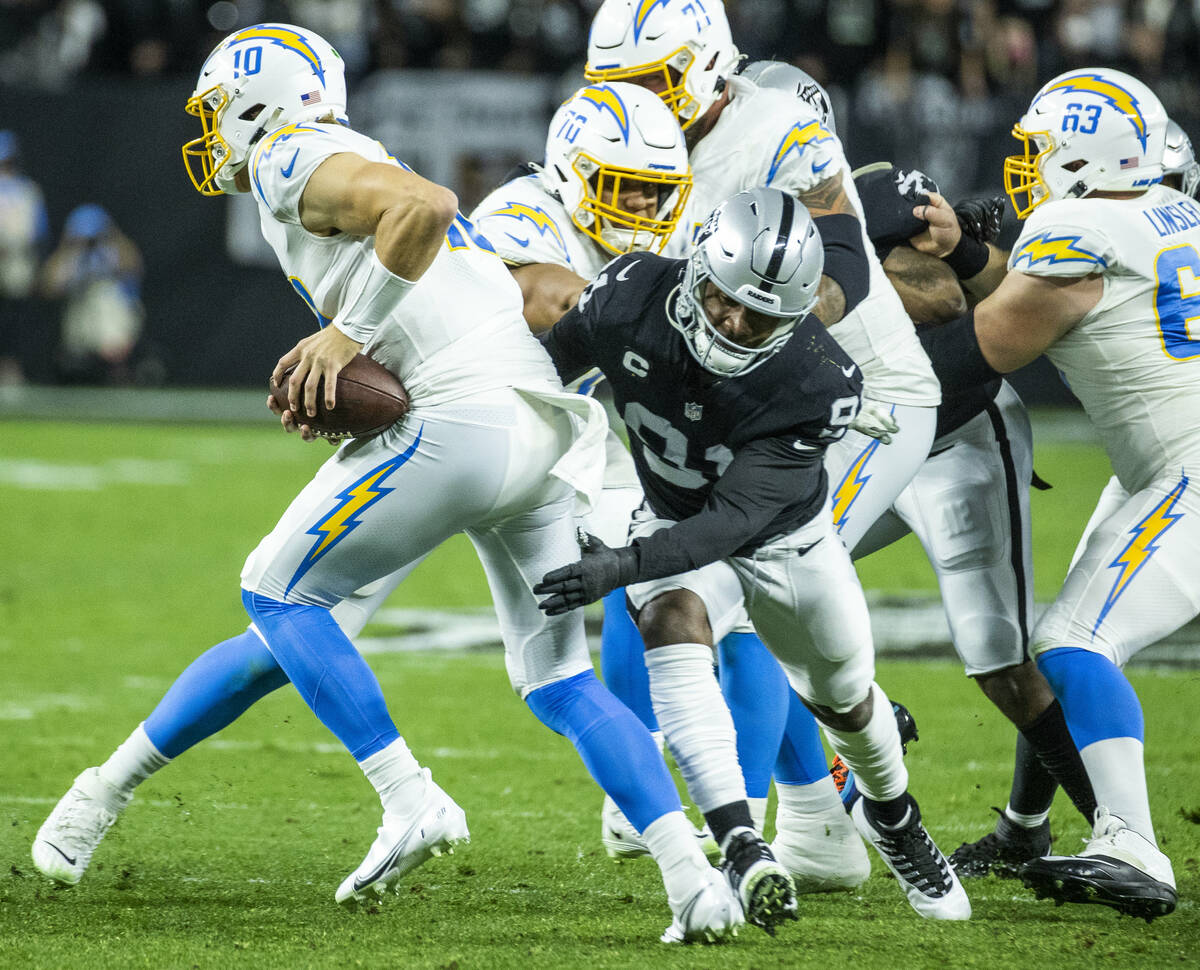 Los Angeles Chargers quarterback Justin Herbert (10) attempts to avoid a sack by Raiders defens ...