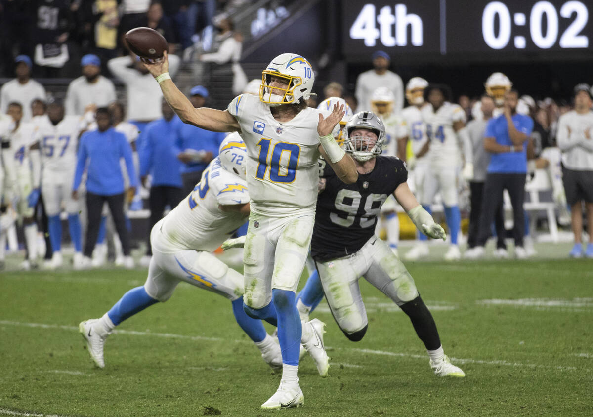 Los Angeles Chargers quarterback Justin Herbert (10) is pressured by Raiders defensive end Maxx ...