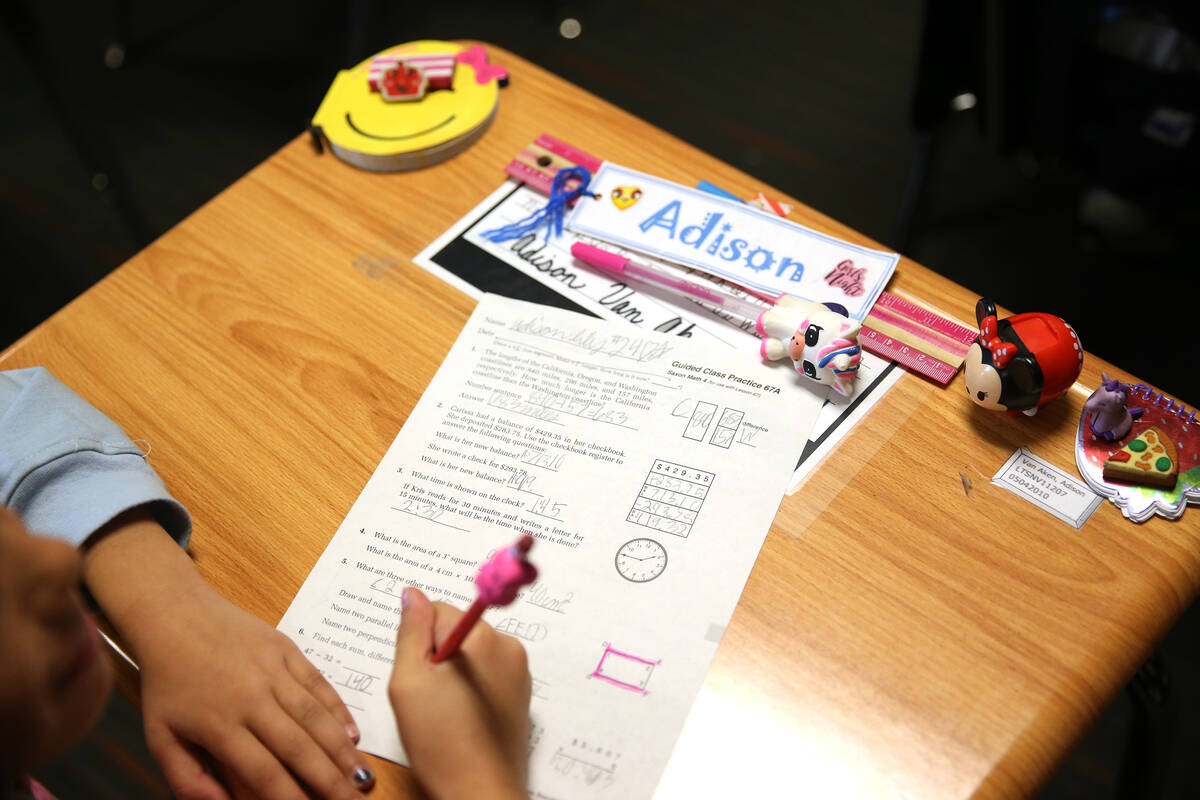 A third-grade student completes her math worksheet during class at Legacy Traditional School in ...