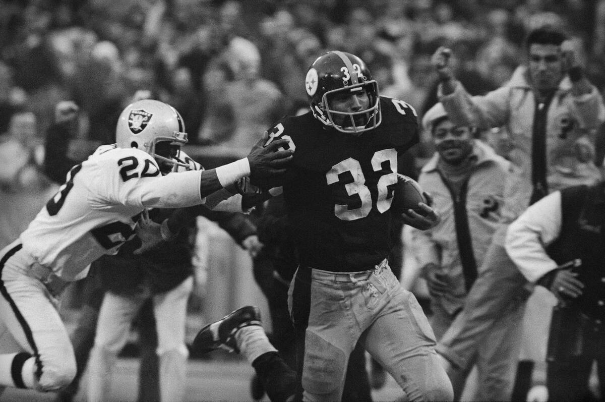 Franco Harris (32) of the Pittsburgh Steelers eludes a tackle by Jimmy Warren of the Oakland Ra ...