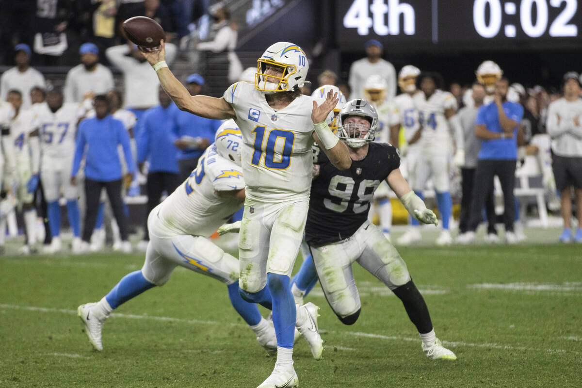 Los Angeles Chargers quarterback Justin Herbert (10) is pressured by Raiders defensive end Maxx ...