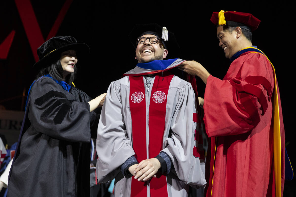 Postgraduate Jaime Carbajal Jr., center, is hooded by Dr. Federick Ngo, right, and UNLV Associa ...
