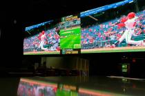 A customer watches a Washington Nationals batter hitting a home run on a giant video screen in ...