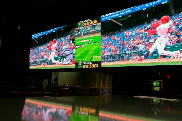A customer watches a Washington Nationals batter hitting a home run on a giant video screen in ...
