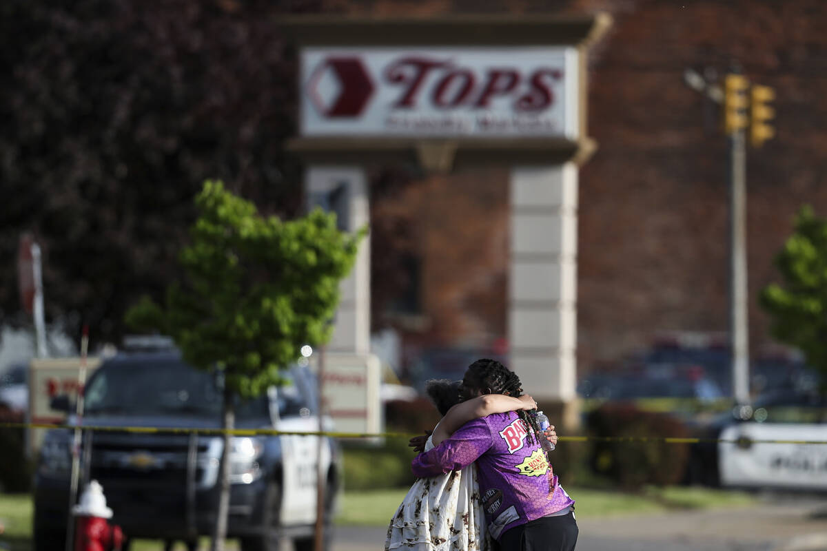 People hug outside the scene after a shooting at a supermarket on Saturday, May 14, 2022, in Bu ...