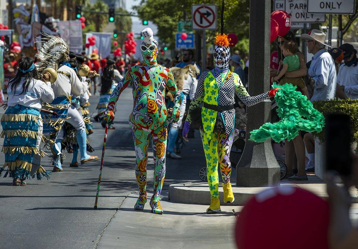 A couple of wild characters stroll along as Native dancers move by during the Las Vegas Day Par ...