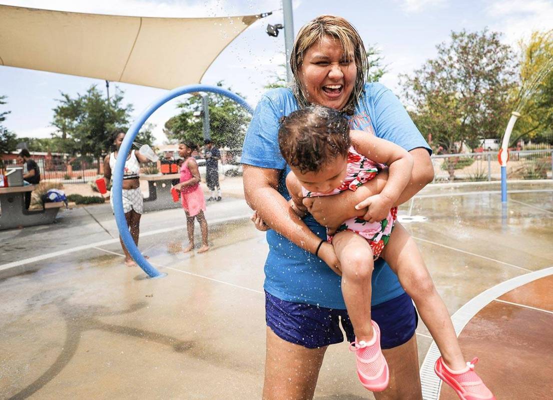Stephanie Ramirez holds her daughter Raylee Brown, 2, as they play in the water at Baker Park i ...
