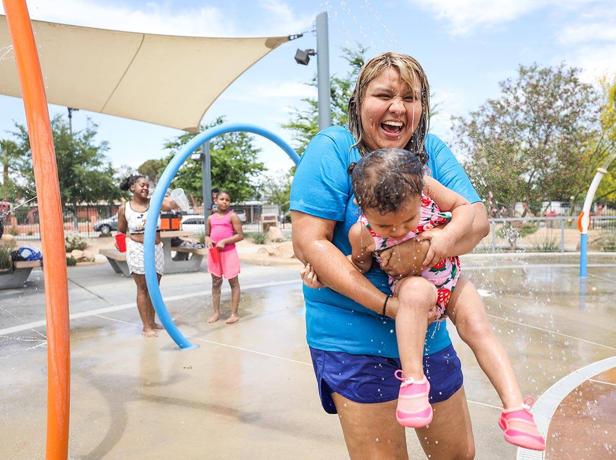 Stephanie Ramirez holds her daughter Raylee Brown, 2, as they play in the water at Baker Park i ...