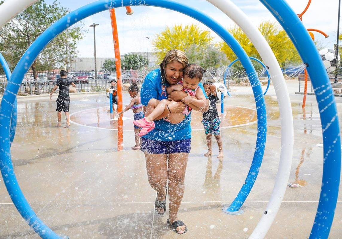 Stephanie Ramirez holds her daughter Raylee Brown, 2, as they play in the water at Baker Park i ...