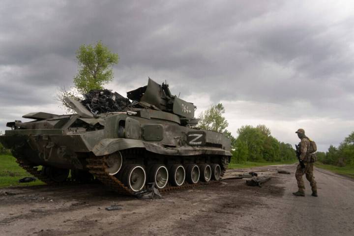 Ukrainian serviceman walks past a blown Russian APC near Kutuzivka, north of Kharkiv, east Ukra ...