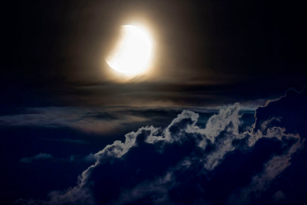A lunar eclipse begins as the full moon sets over the hills of the Taunus mountains near Frankf ...