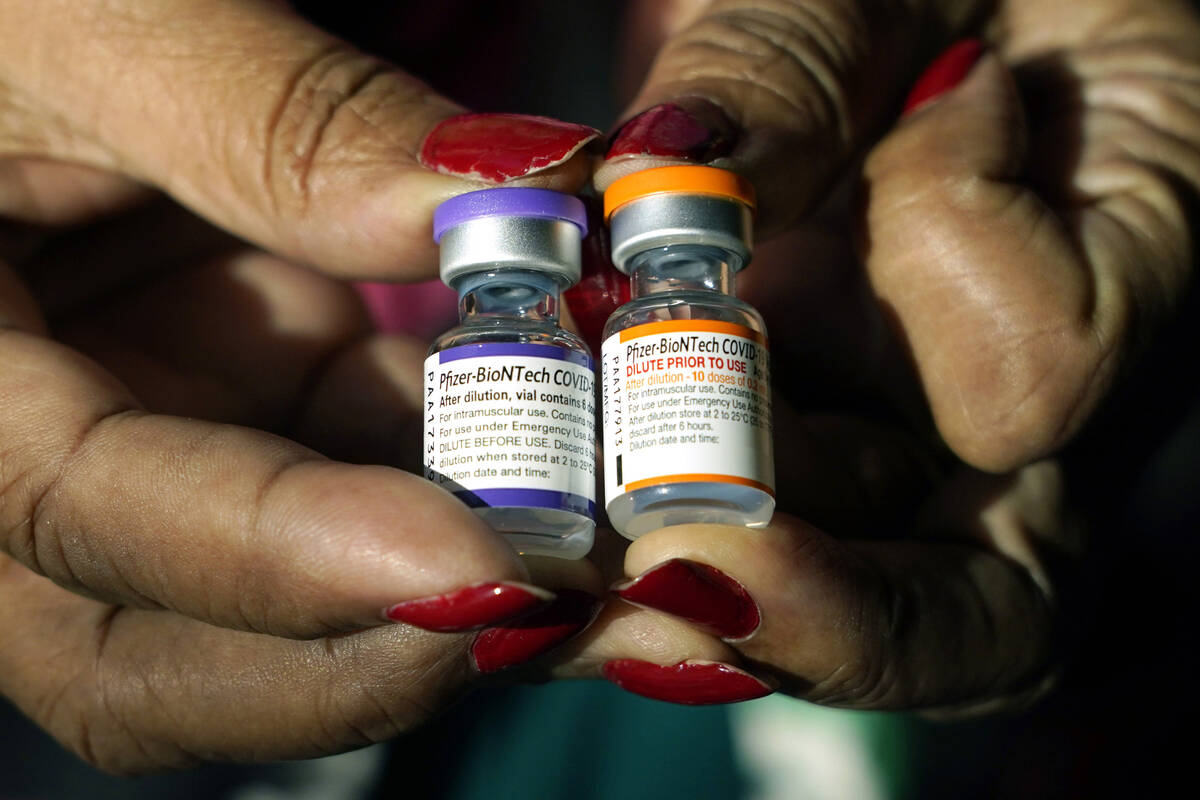 FILE - A nurse holds a vial of the Pfizer COVID-19 vaccine for children ages 5 to 11, right, an ...