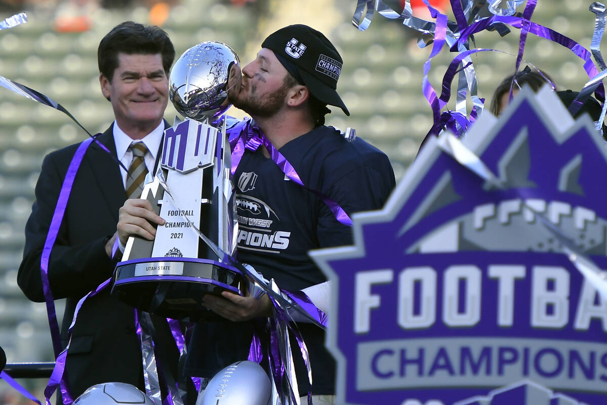 Craig Thompson, Mountain West Conference commissioner, stands next to Utah State quarterback Lo ...