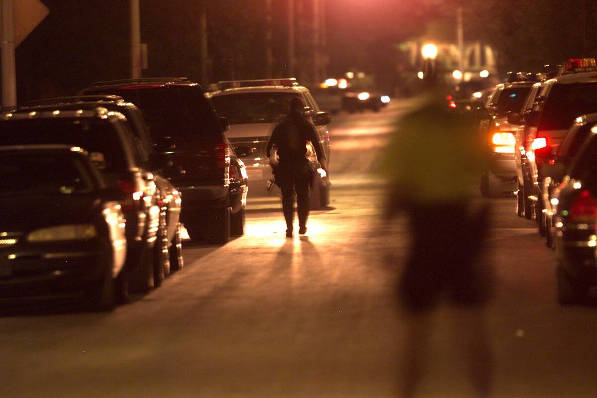 A SWAT officer walks down First Street near Bonanza Road on Sunday, April 14, 2002, in search T ...