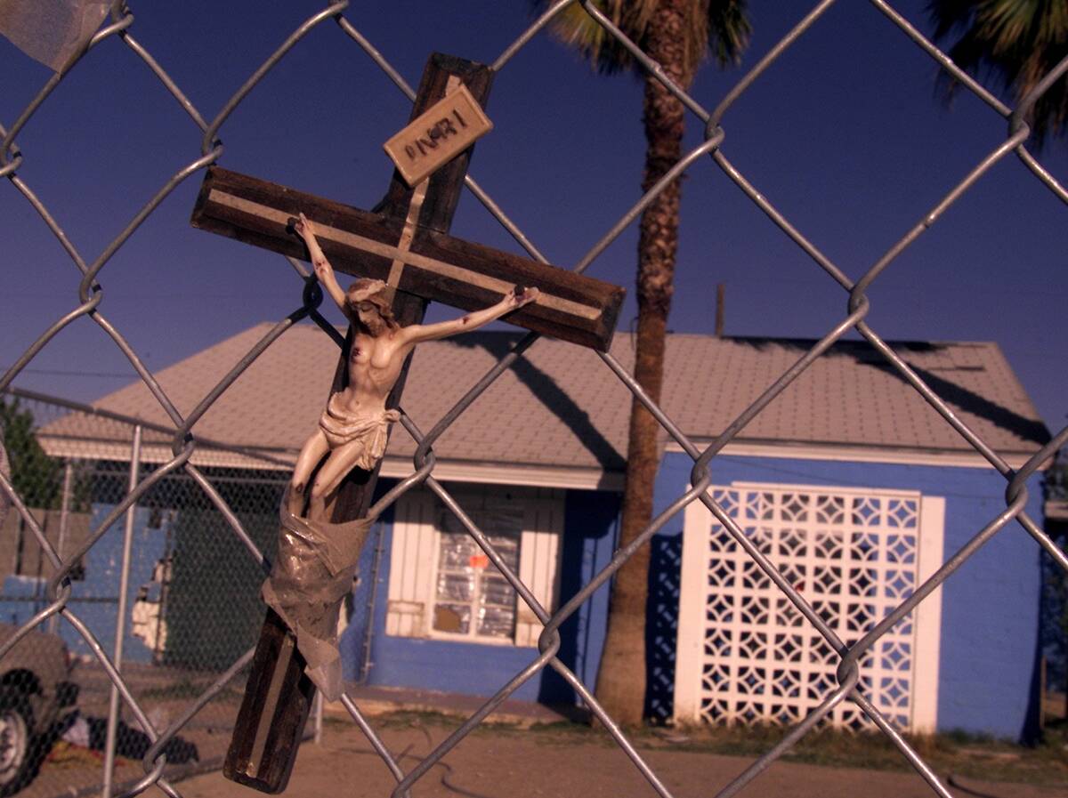 A crucifix hangs on a fence in front of the home where Timmy "T.J." Weber killed Kim ...