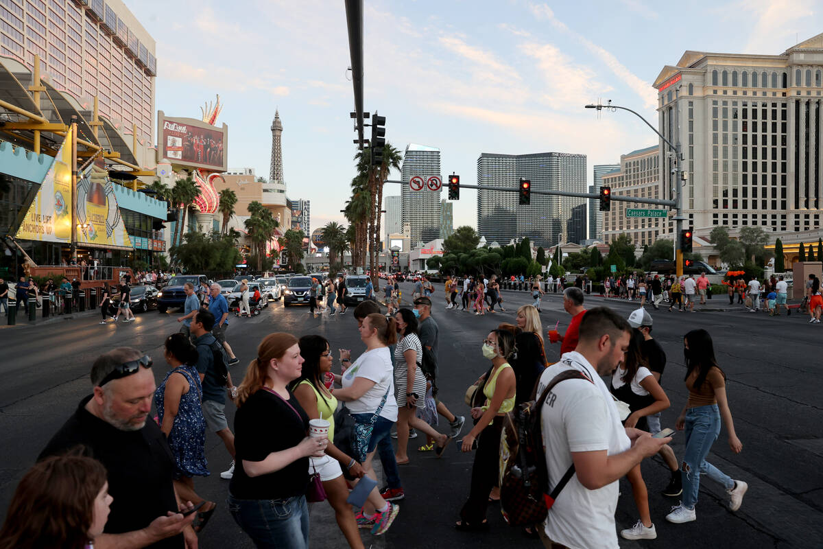 Crowds cross the Strip at between the Linq Promenade and Caesars Palace in Las Vegas Friday, Ma ...