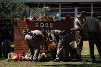 Two Texas Troopers light a candle at Robb Elementary School in Uvalde, Texas, Wednesday, May 25 ...