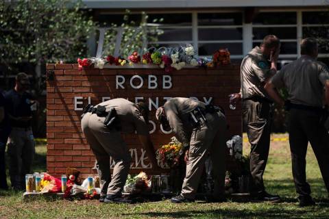 Two Texas Troopers light a candle at Robb Elementary School in Uvalde, Texas, Wednesday, May 25 ...