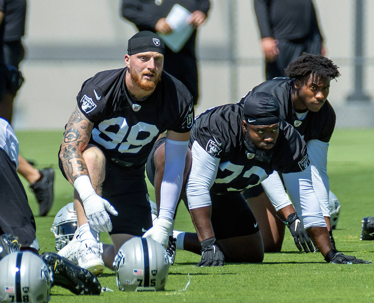 Raiders defensive end Maxx Crosby (98) looks up beside defensive tackle Matthew Butler (73) and ...