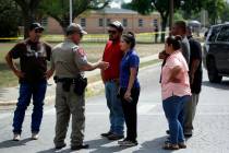 A policeman talks to people asking for information outside of the Robb Elementary School in Uva ...