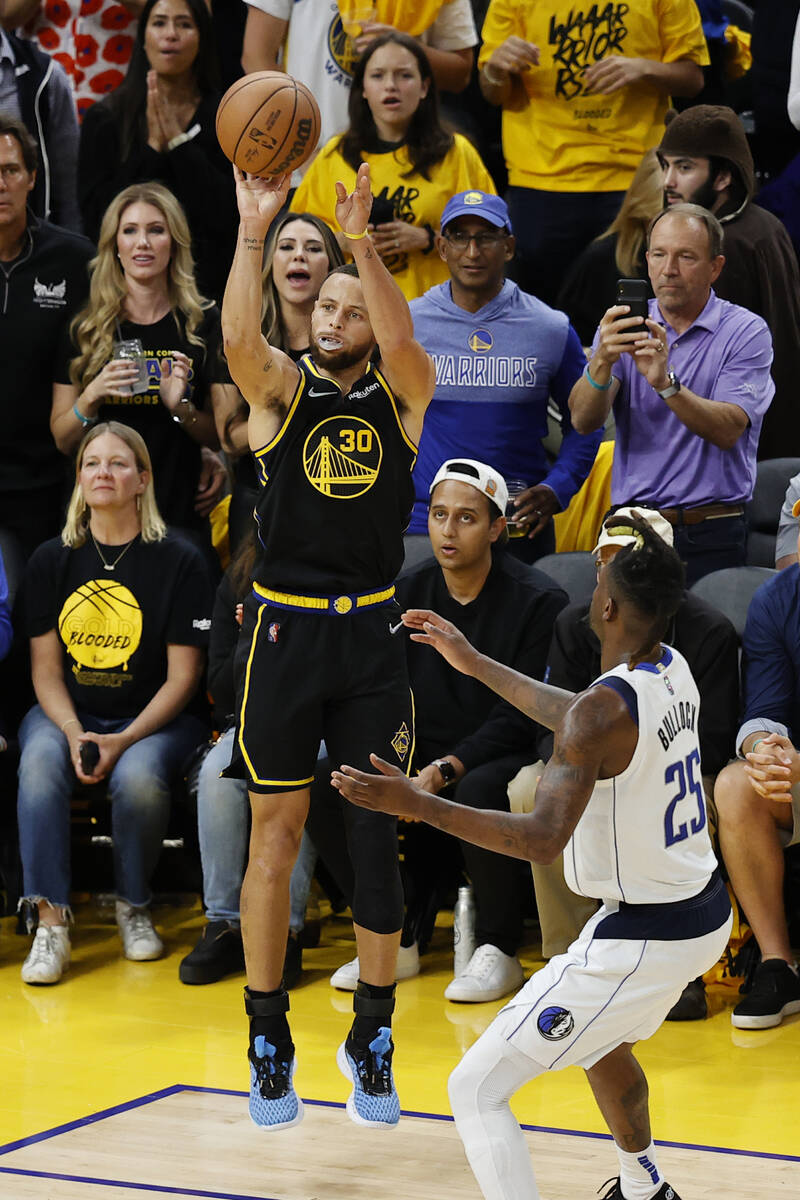 Golden State Warriors guard Stephen Curry, top left, makes a 3-point basket over Dallas Maveric ...