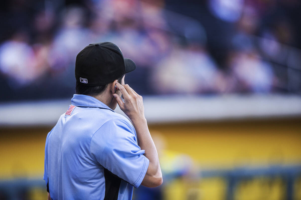 Home plate umpire Takahito Matsuda adjusts the ear piece connected to the Automated Ball-Strike ...
