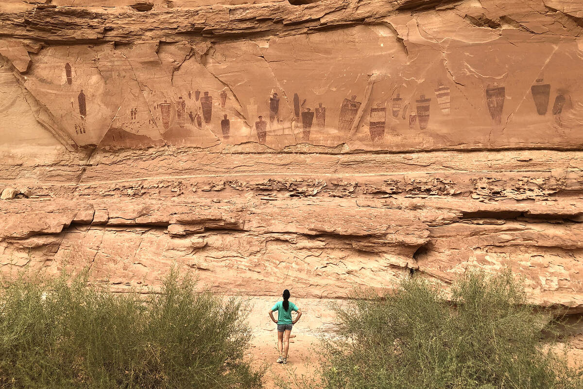 A hiker pauses to view the Great Gallery, a 200-foot panel of ancient drawings along the dry cr ...