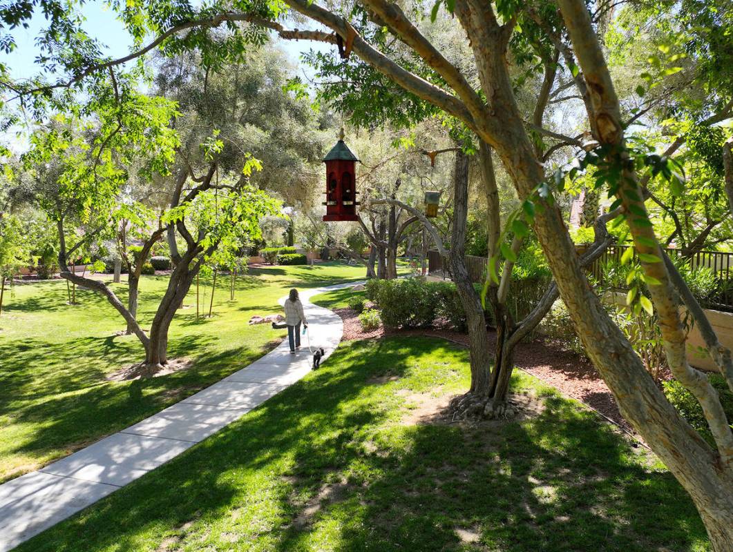 A woman walks with her dog past birdhouses along a walking trail in Peccole Ranch in Summerlin. ...