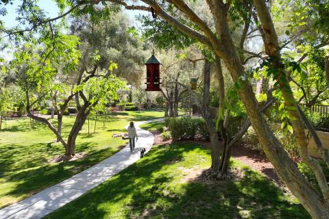 A woman walks with her dog past birdhouses along a walking trail in Peccole Ranch in Summerlin. ...