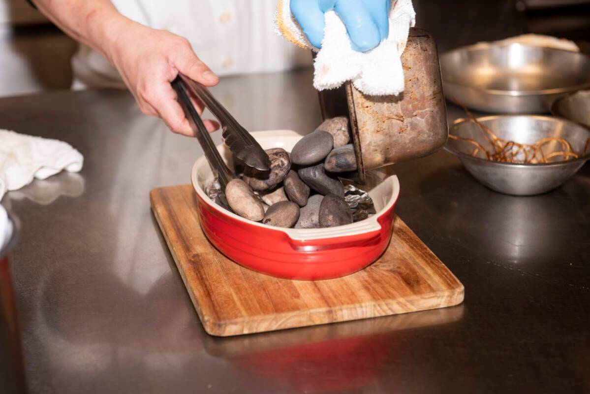 A member of the kitchen prepares the hot stones for the Chef's Special Short Rib Served on Ishi ...