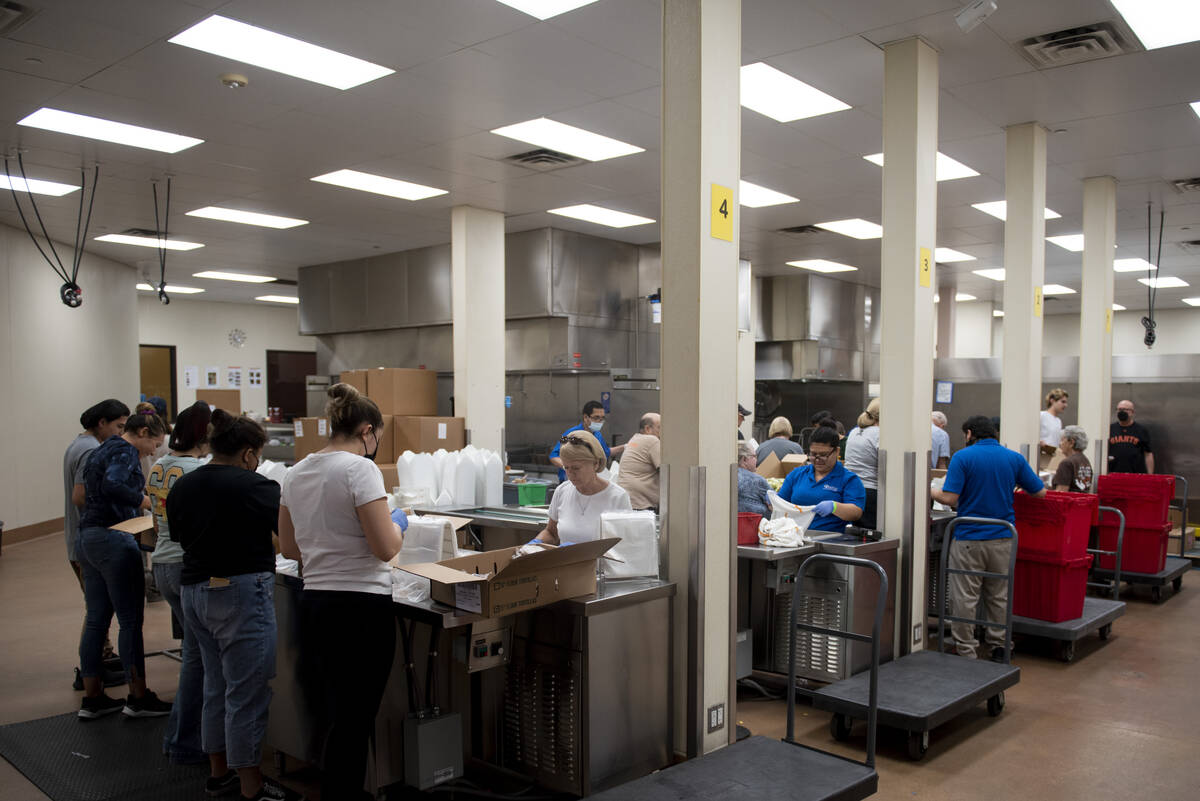 Volunteers help pack lunches for students on summer break at Three Square, the food bank servin ...
