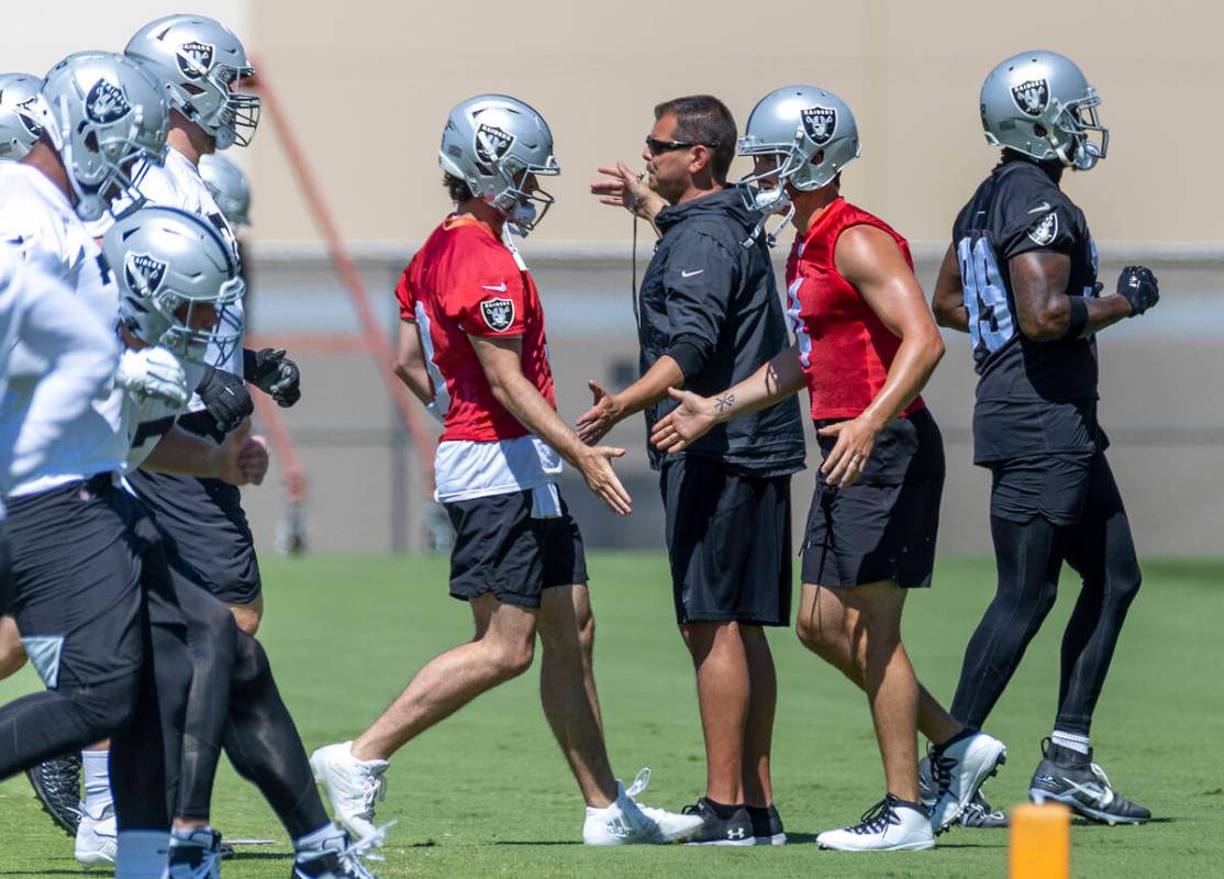 Raiders quarterback Jarrett Stidham (3, left) greets teammate Derek Carr (4) while running a dr ...
